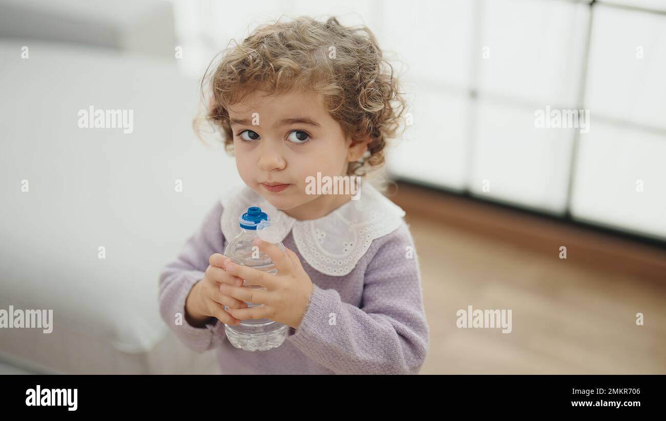 Adorable hispanic girl drinking water standing at home Stock Photo