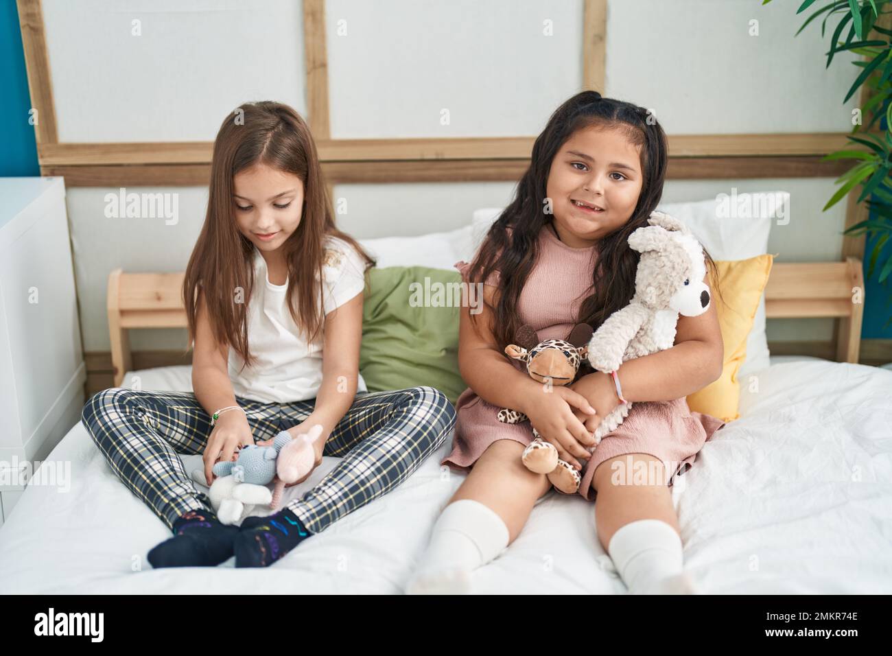 Two kids playing with dolls sitting on bed at bedroom Stock Photo - Alamy