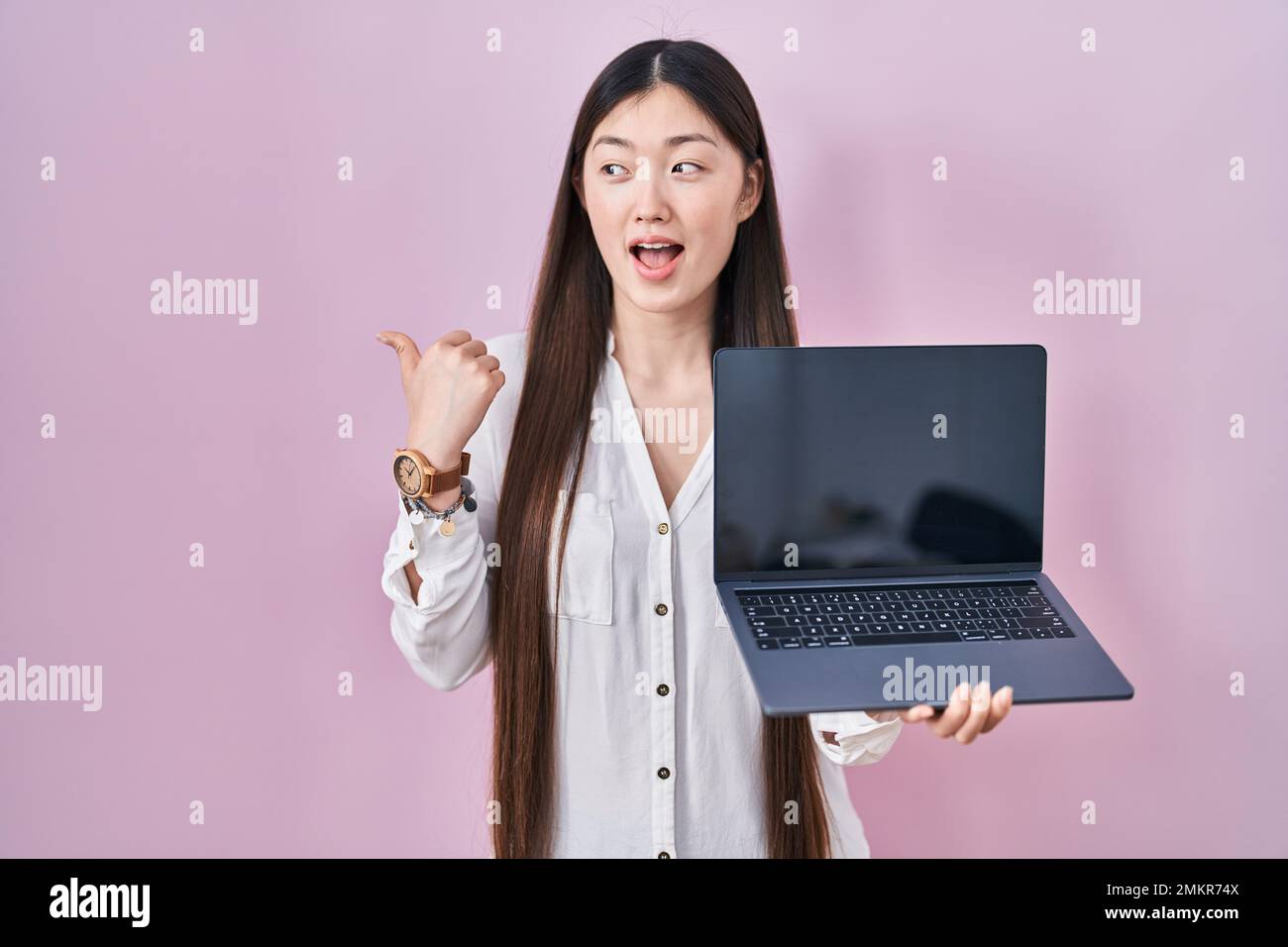 Chinese young woman holding laptop showing screen pointing thumb up to ...