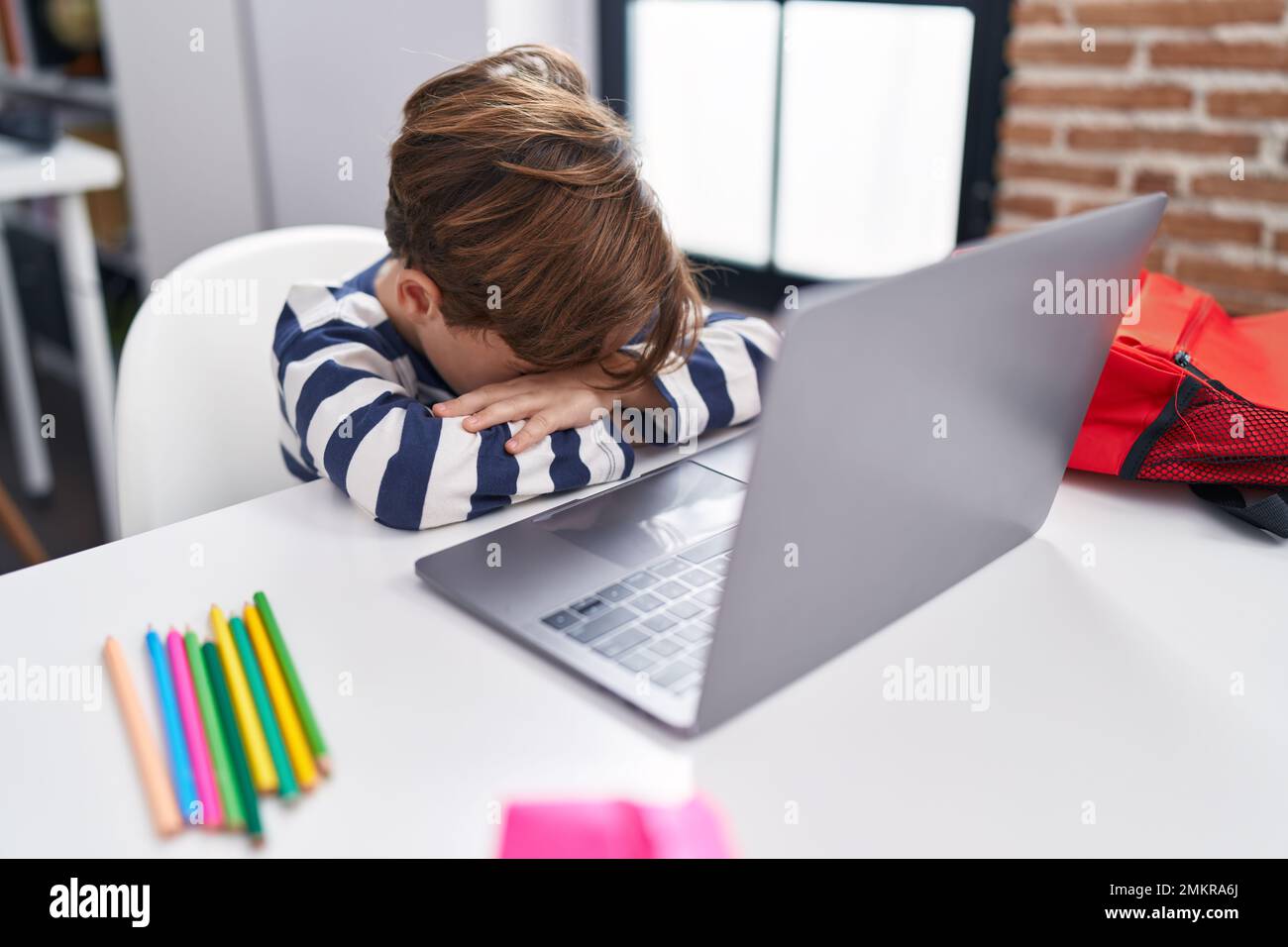 Adorable hispanic boy student using computer with stressed expression ...