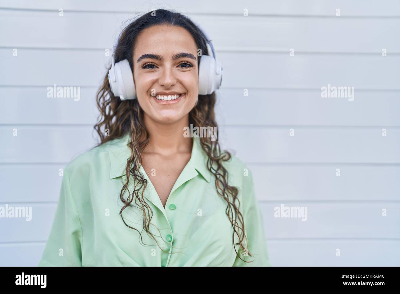 Young hispanic woman listening to music using headphones looking ...