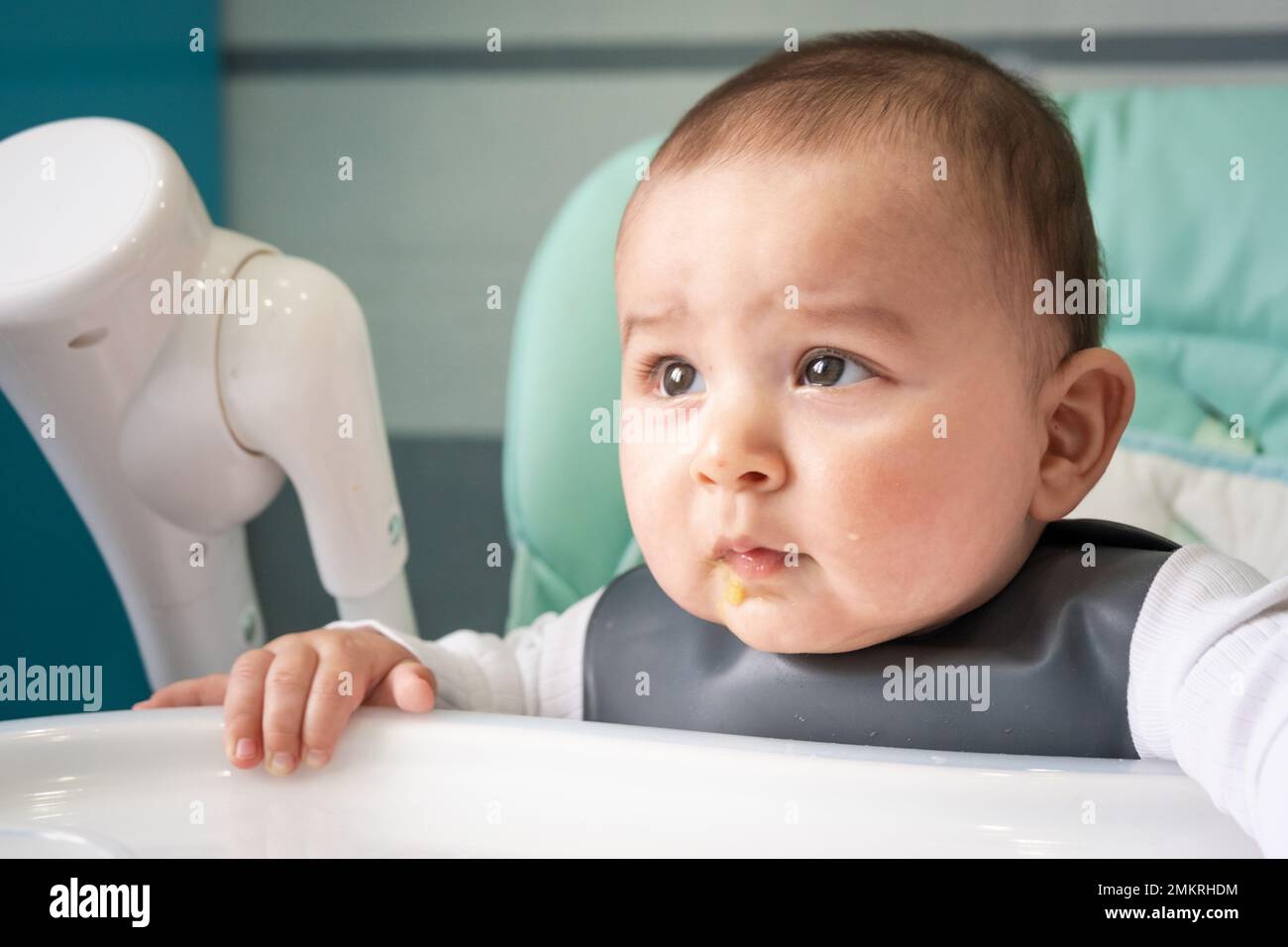 The baby is naughty at the table on the high chair. Hungry upset child