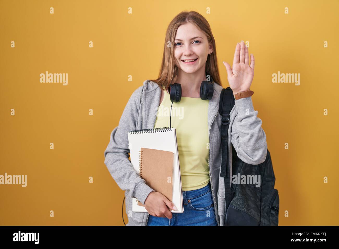 Young caucasian woman wearing student backpack and holding books ...