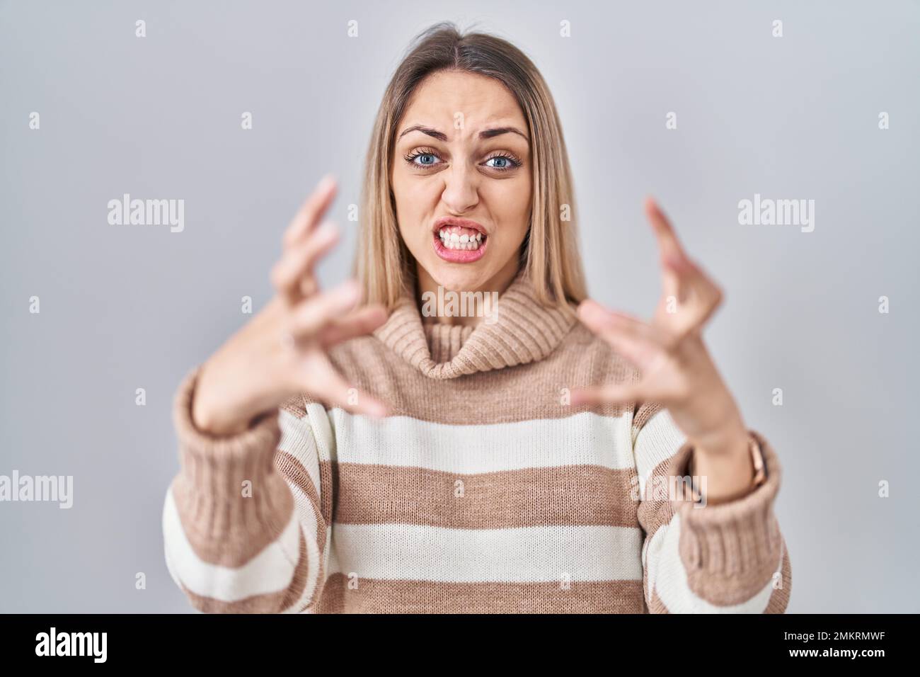 Young blonde woman wearing turtleneck sweater over isolated background