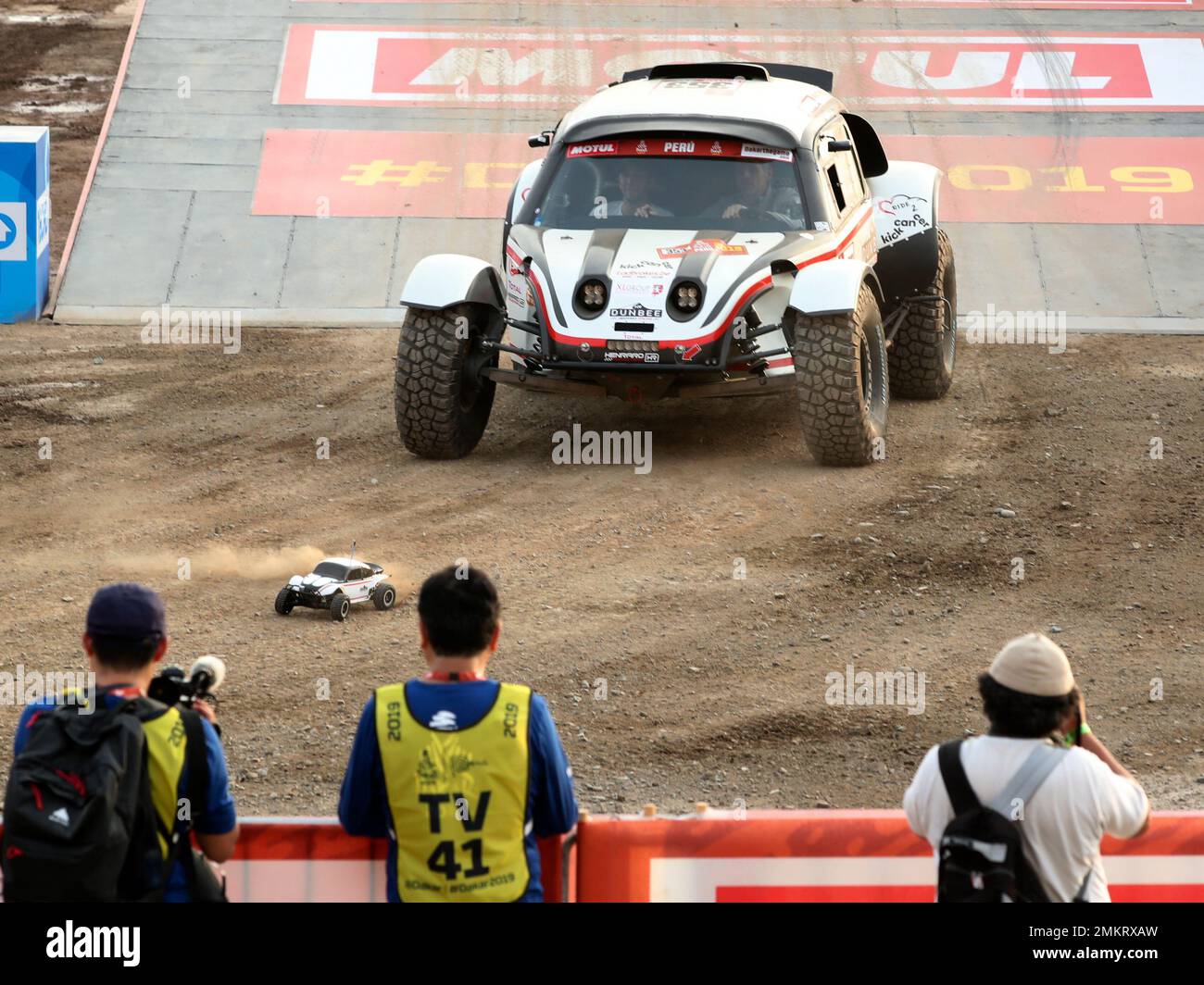 Driver Stephane Henrard and co-driver Gatien Du Bois, both of Belgium,  follow a radio controlled replica of their Henrard Racing during the podium  ceremony before the start of the Dakar Rally in