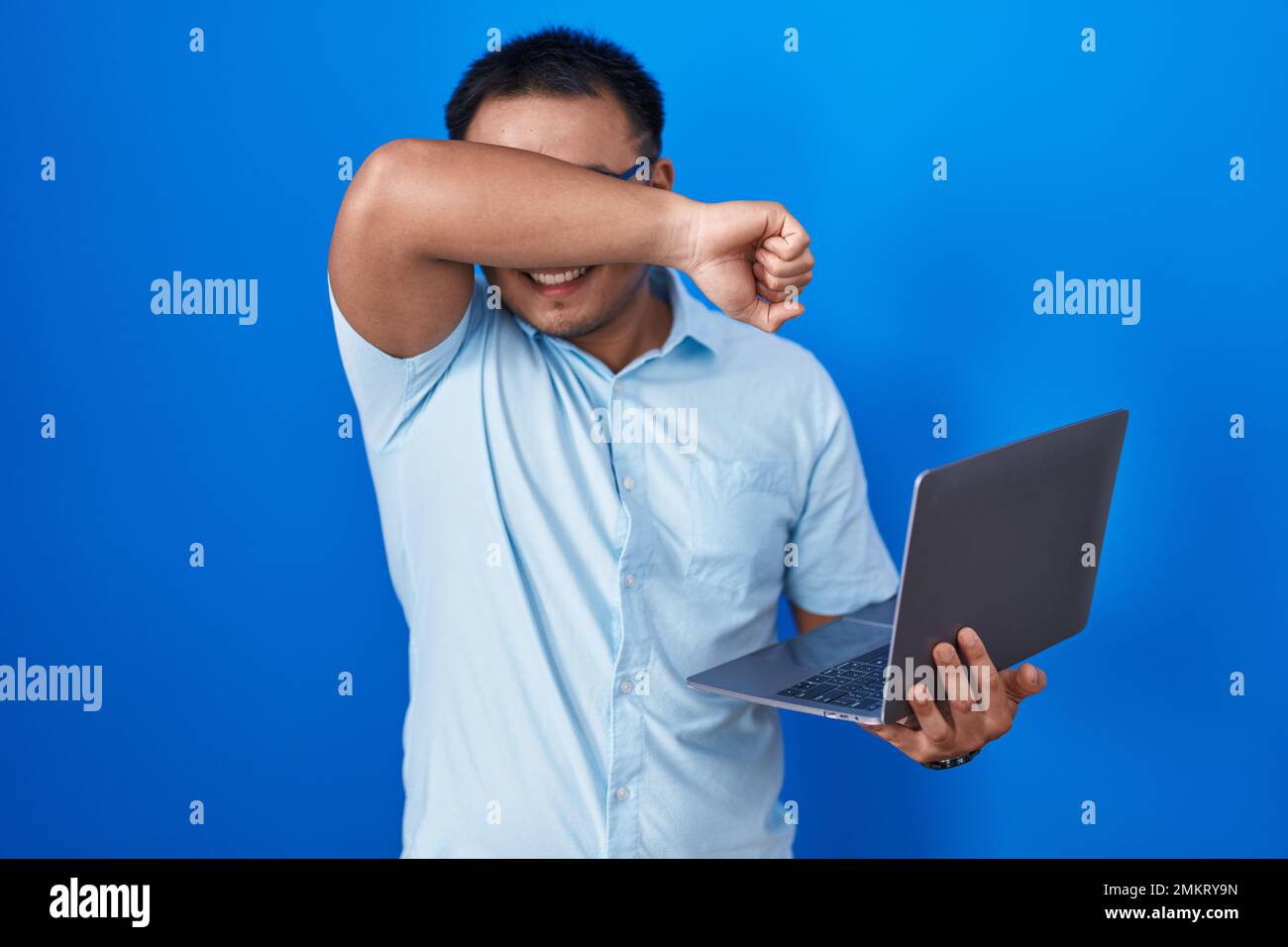 Chinese young man using computer laptop smiling cheerful playing peek a ...