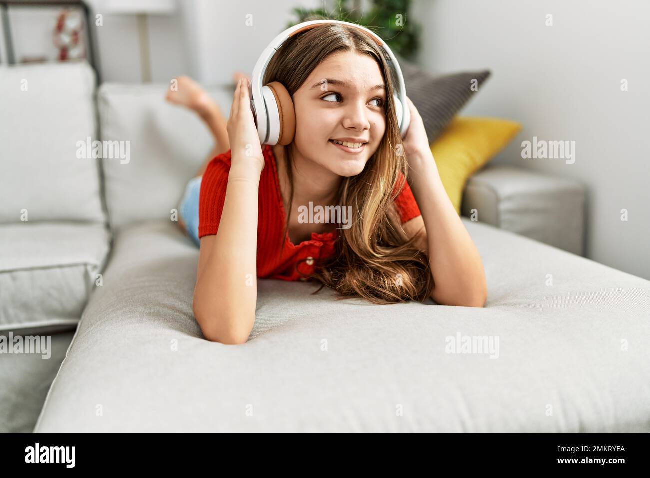 Adorable girl listening to music lying on sofa at home Stock Photo - Alamy