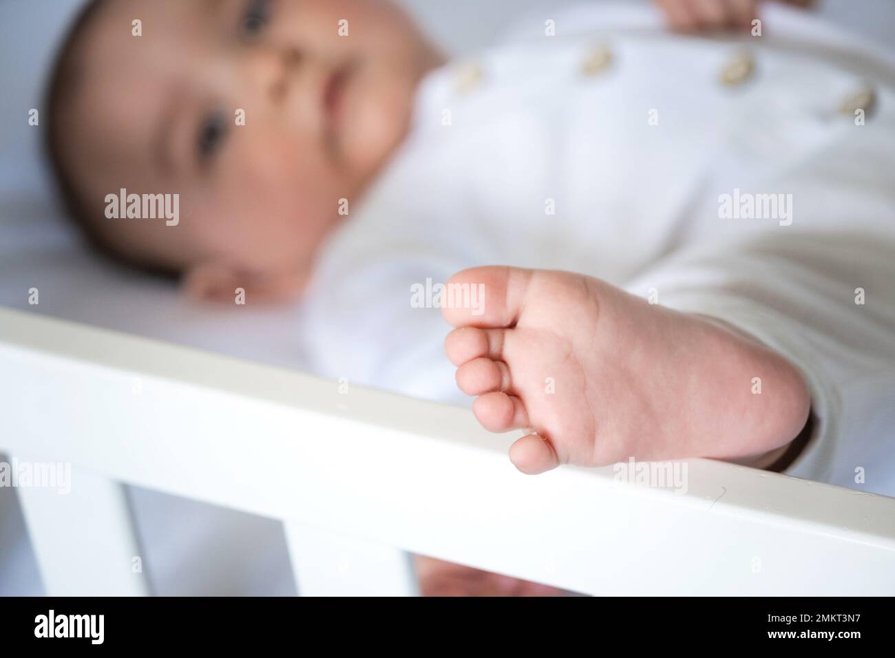 The baby's leg is closeup, the child is lying in bed. Baby care