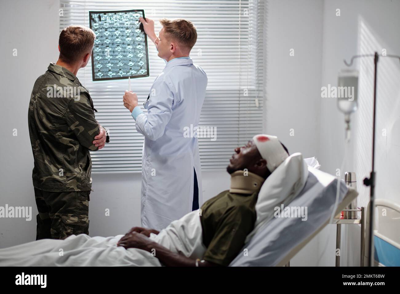 Radiologist showing x-ray image of soldiers spine discs to sergeant and explaining recovery process Stock Photo