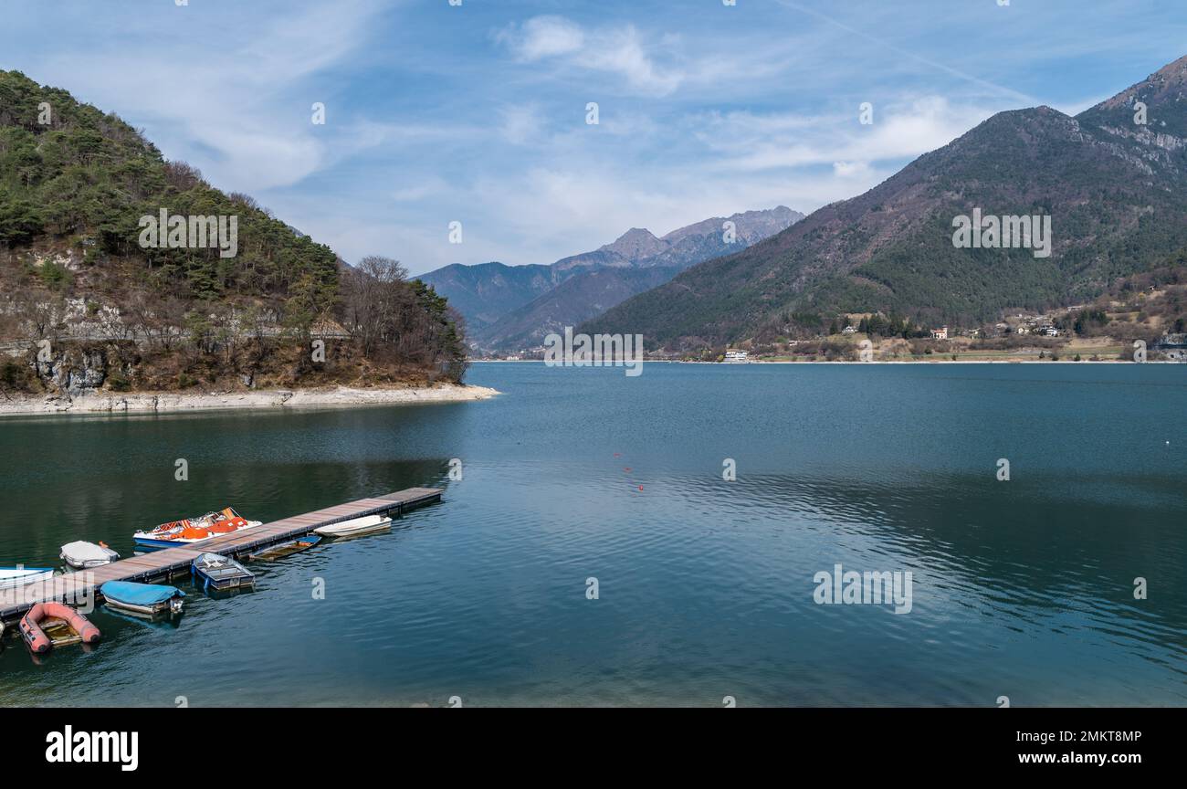 Lake Ledro (Ledro Valley) and the surrounding mountains on a clear spring day. A boat landing stage and some boats. Trento province, Trentino Alto-Adi Stock Photo