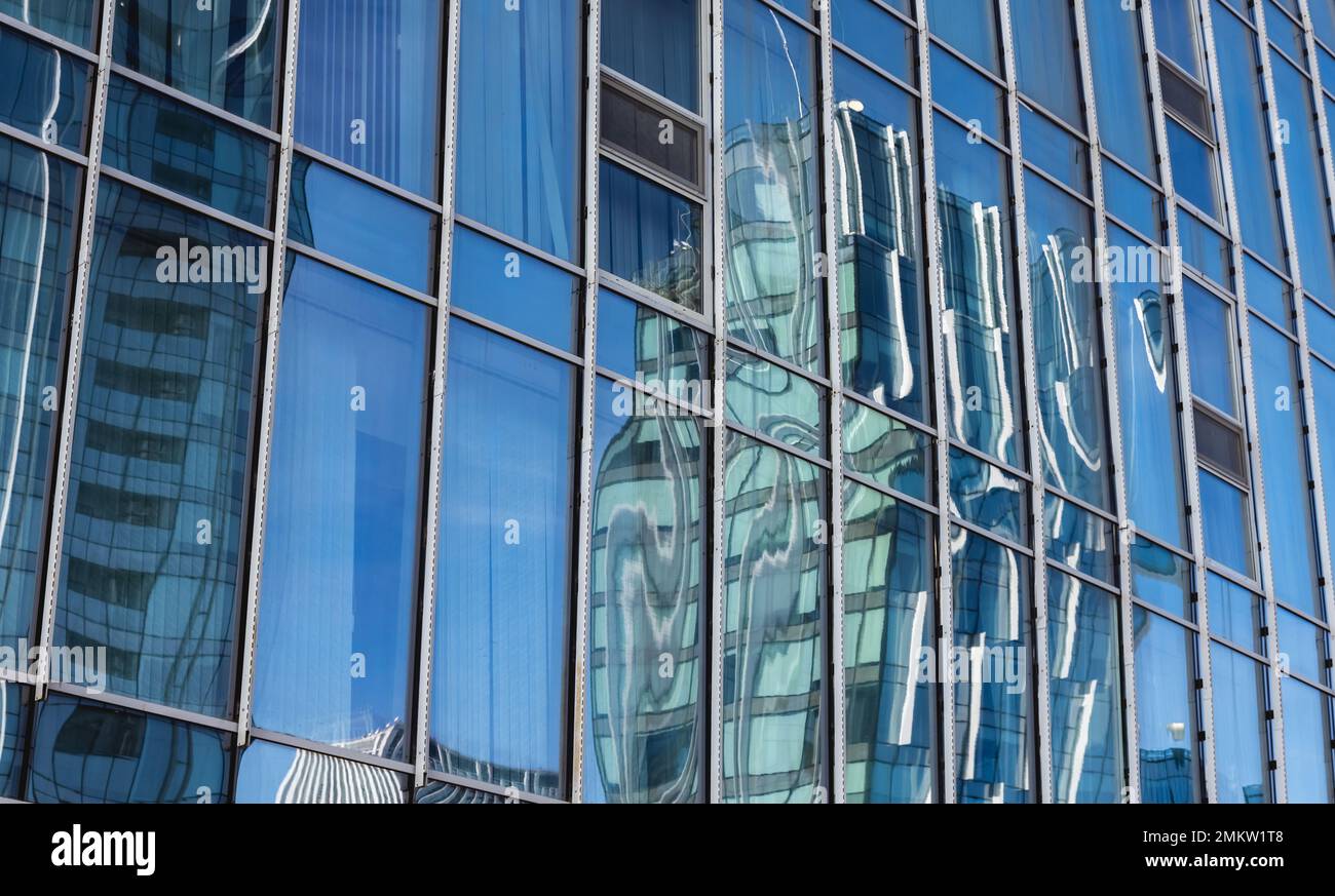 The blue sky is reflected in the windows of a modern office building ...