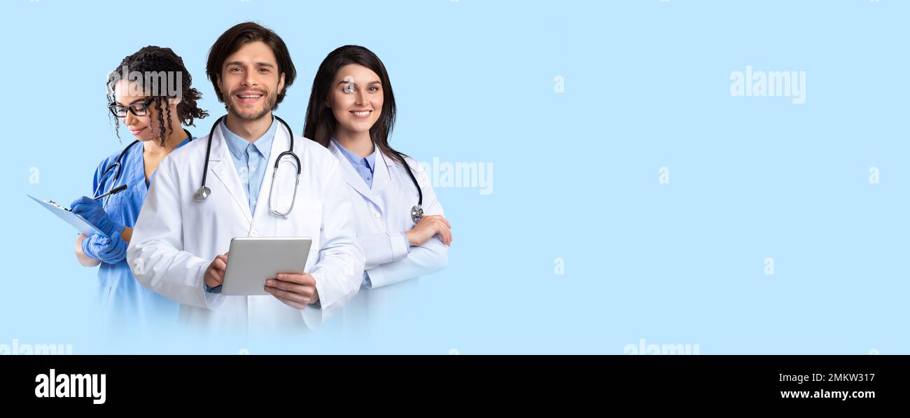Friendly smiling multiethnic doctors posing on blue, holding digital tablet Stock Photo