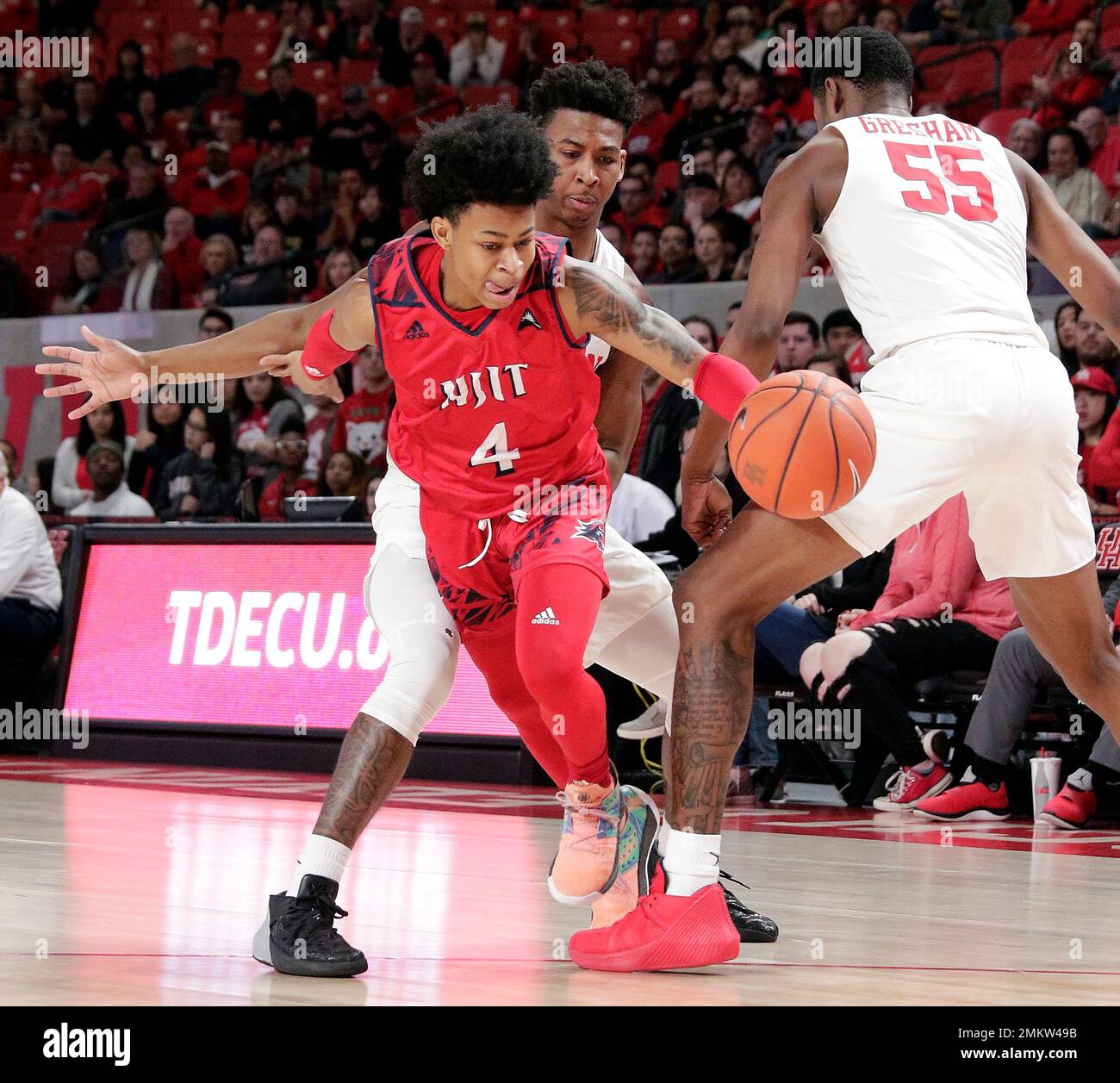 New Jersey Institute of Technology guard Zach Cooks (4) drives the ball  between Houston guard Nate Hinton, center, and forward Brison Gresham (55)  Saturday, Dec. 29, 2018, in Houston. (AP Photo/Michael Wyke