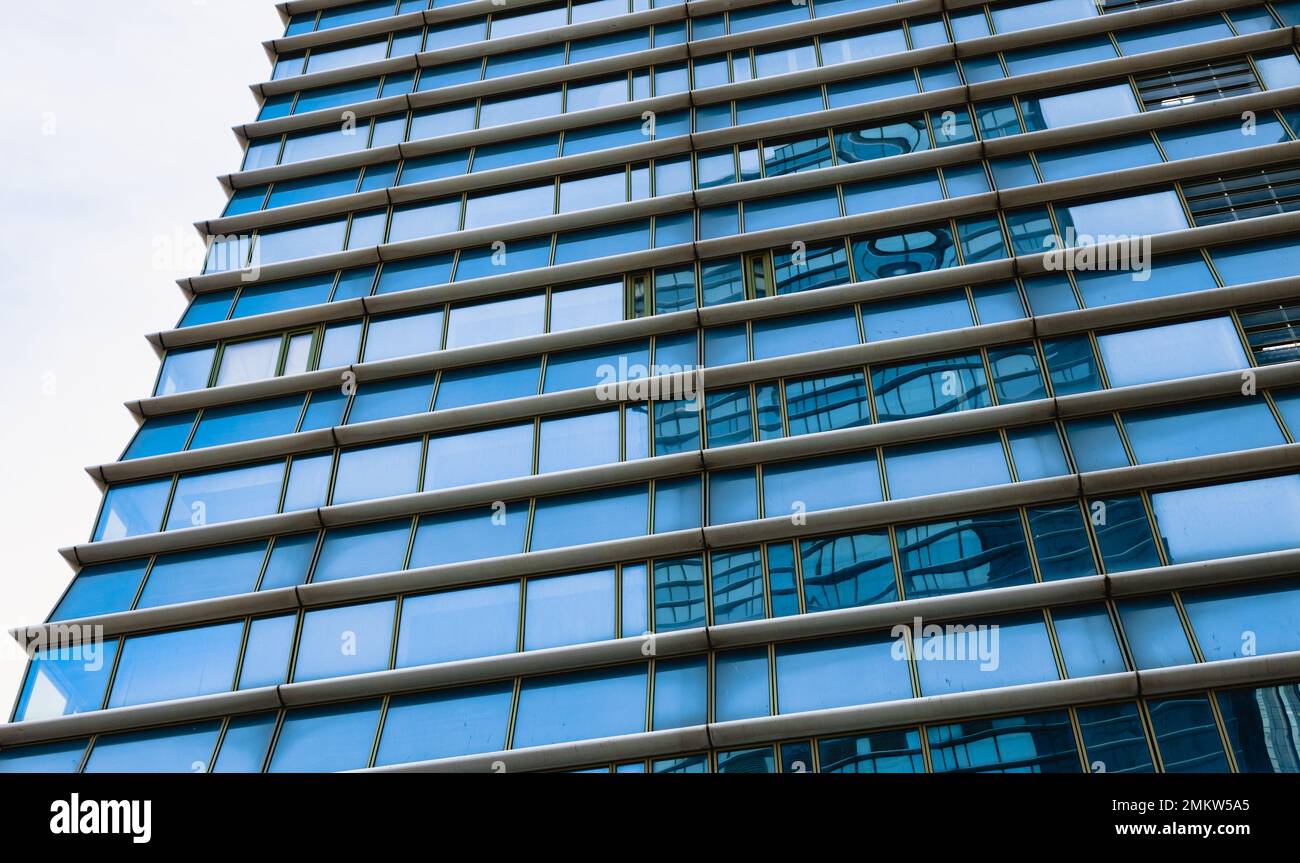 The blue sky is reflected in the windows of a modern office building ...