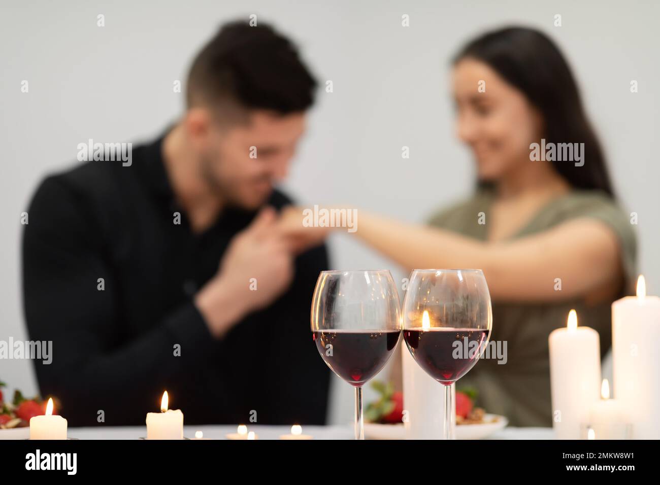 Selective focus on glasses with red wine over bonding couple Stock Photo