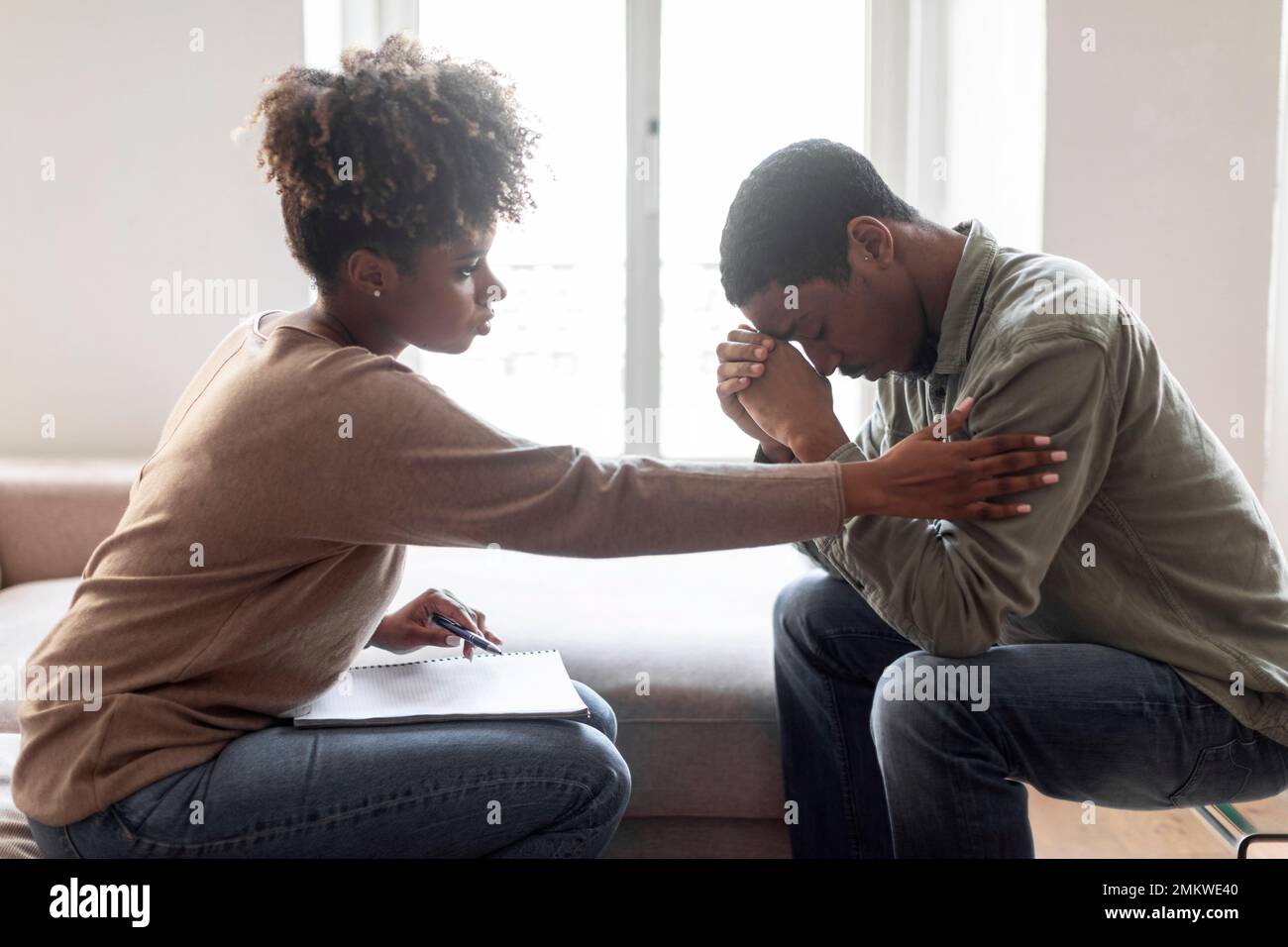 Black woman psychologist comforting upset man patient, side view Stock Photo