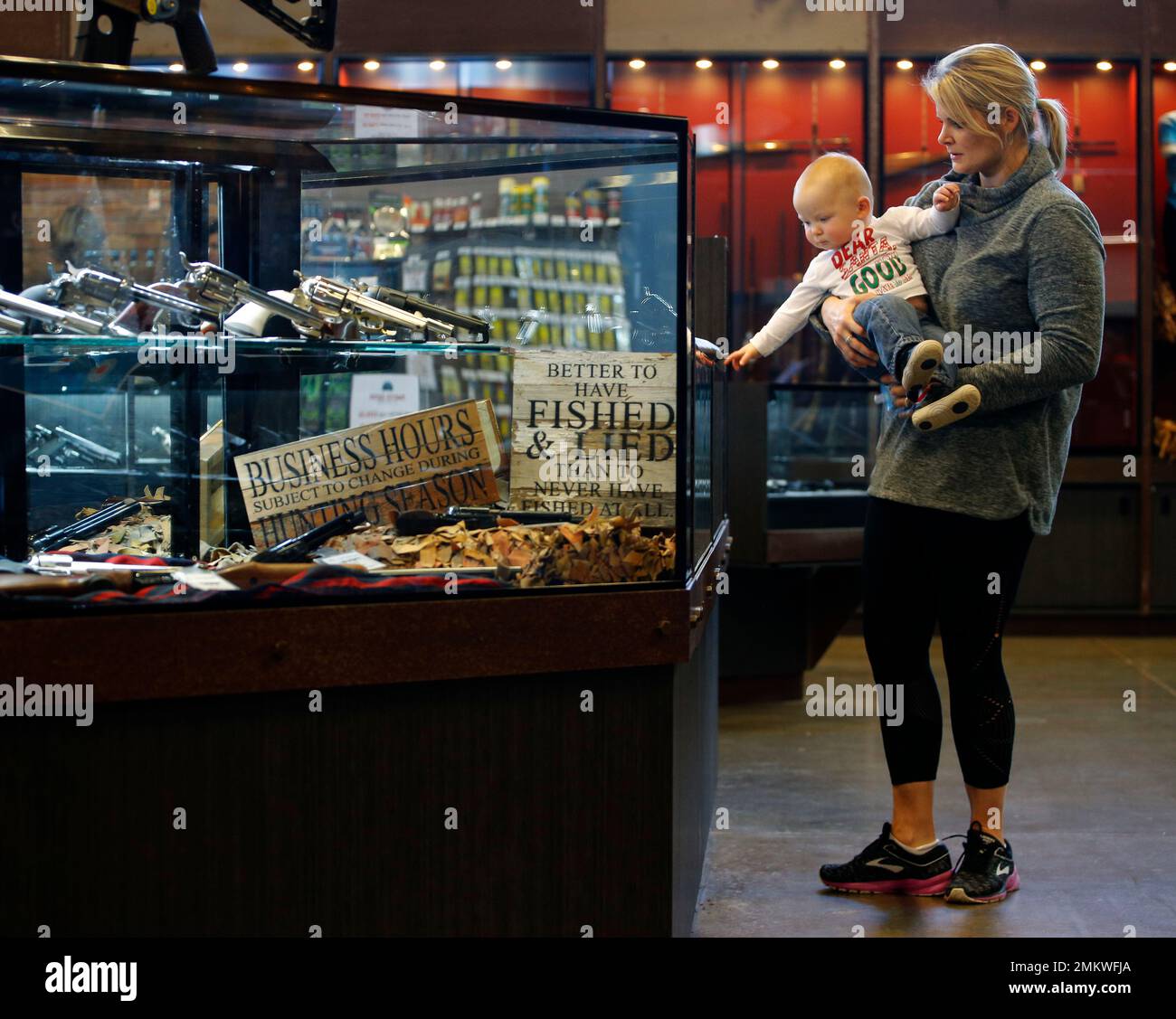In this photo taken Friday, Dec. 21, 2108, Anne Vifquain shops for a gun  with her son Gavin, age 1, at Frontier Justice in Lee's Summit, Mo. The  store caters to women
