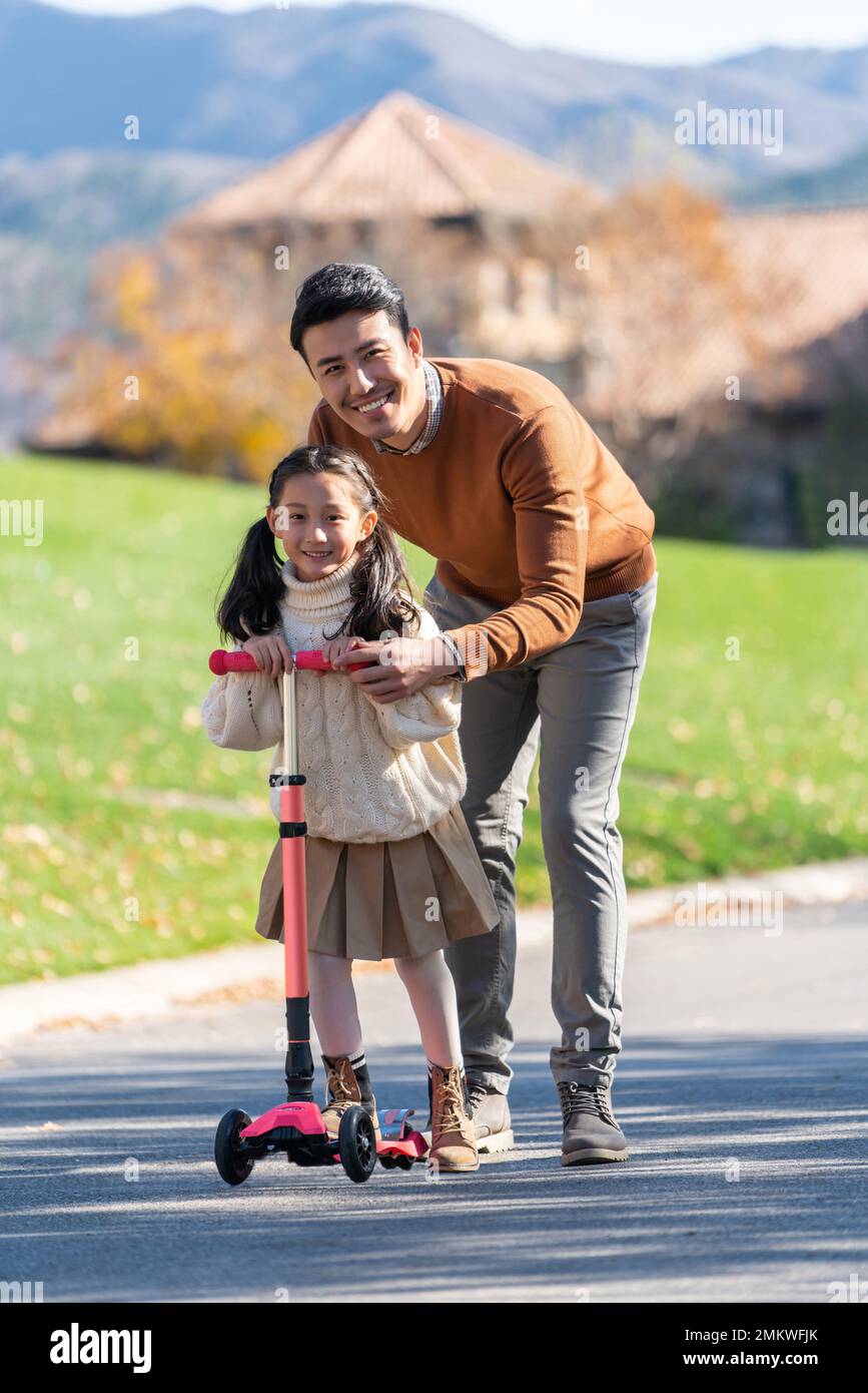 Father with children playing scooter Stock Photo