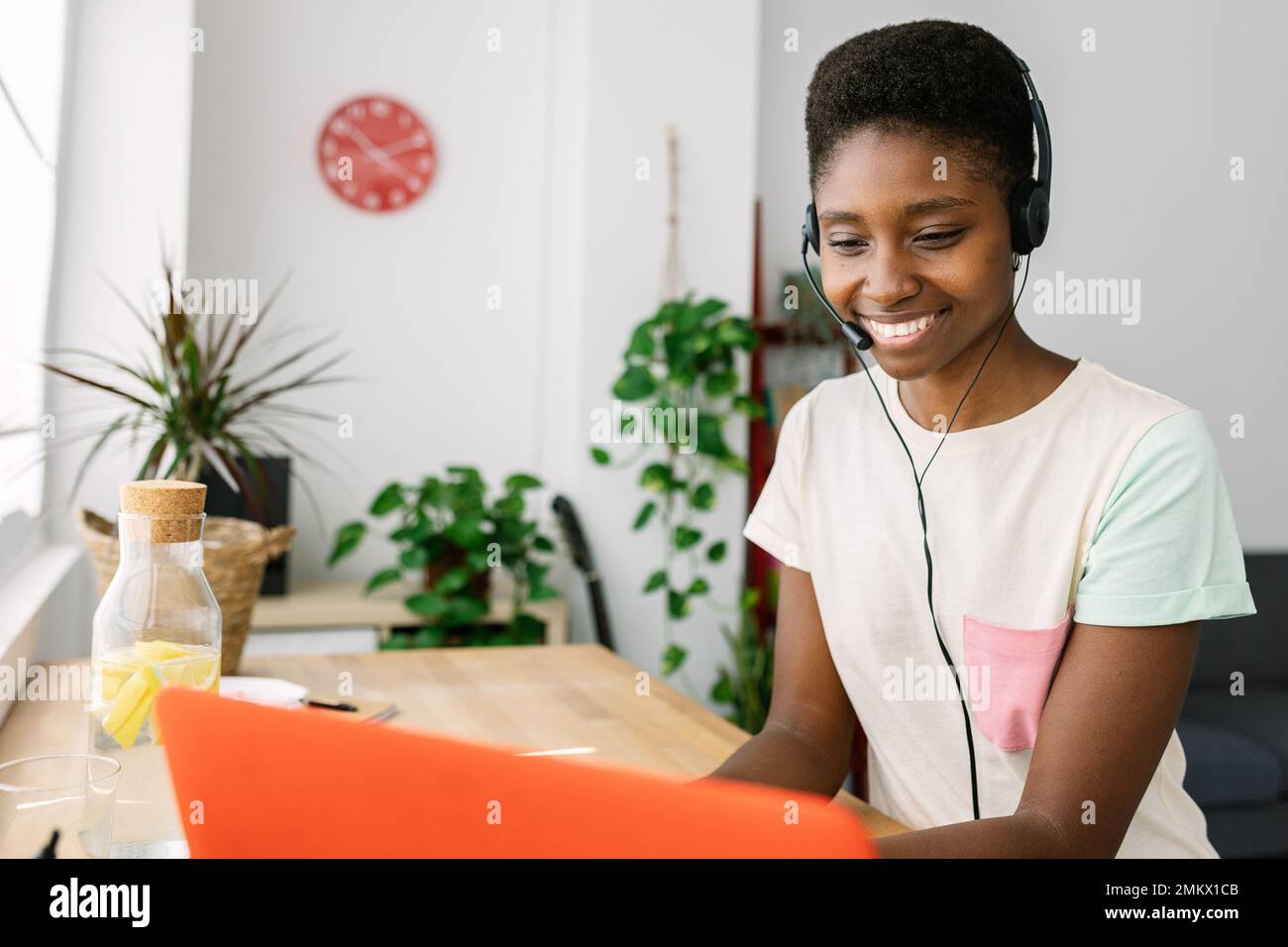Young african woman with headset having a video call with laptop from home Stock Photo