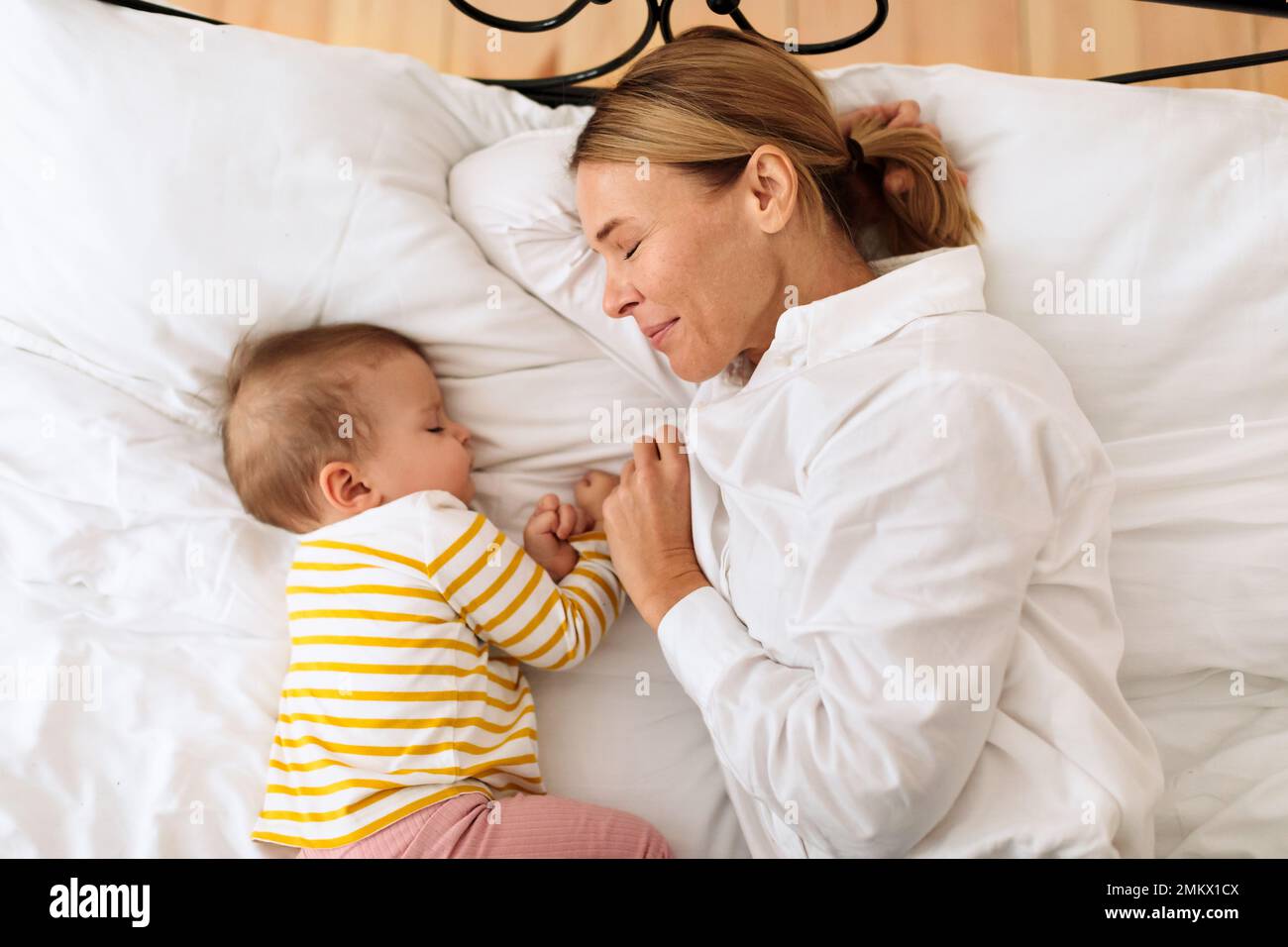 Cosleeping with baby. Mother napping in bed with her cute newborn