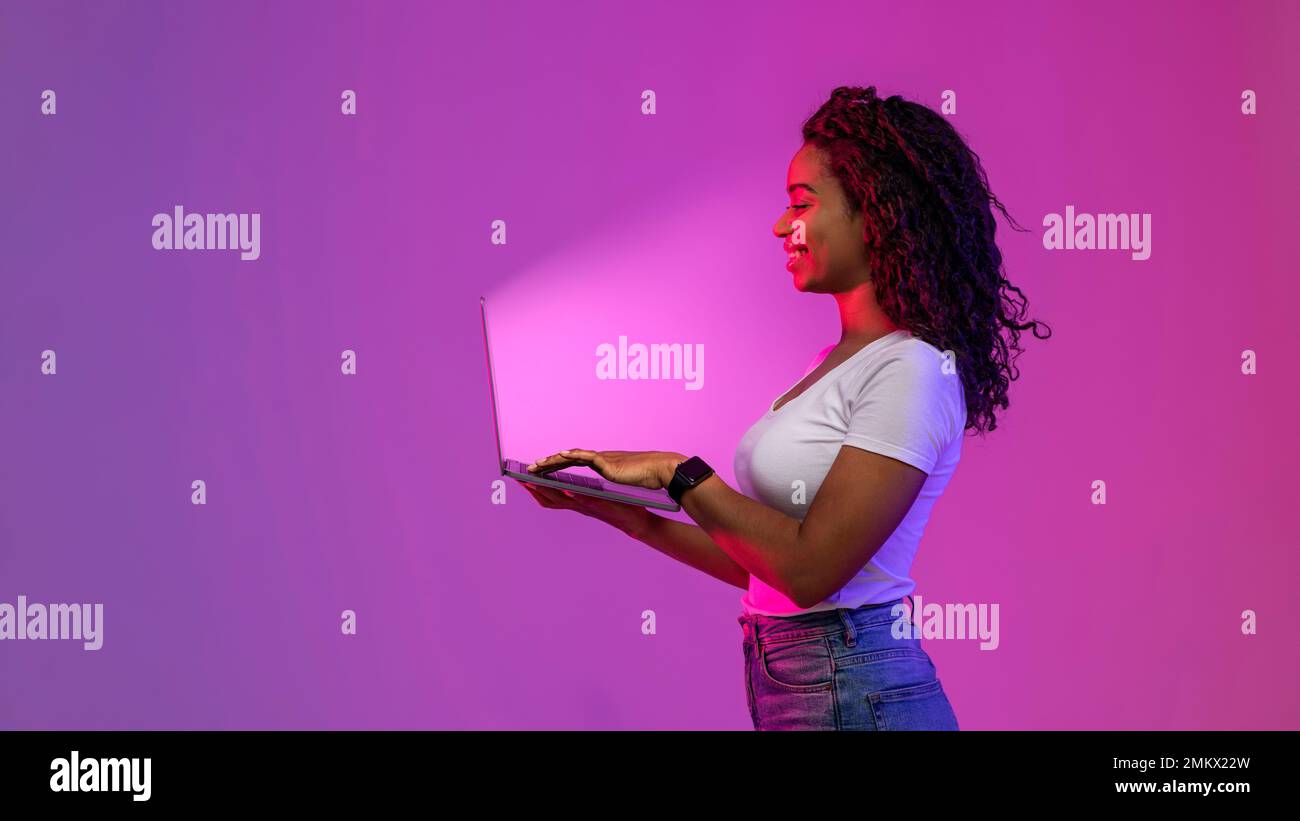 Smiling Black Woman Holding Laptop And Looking At Glowing Screen Stock Photo