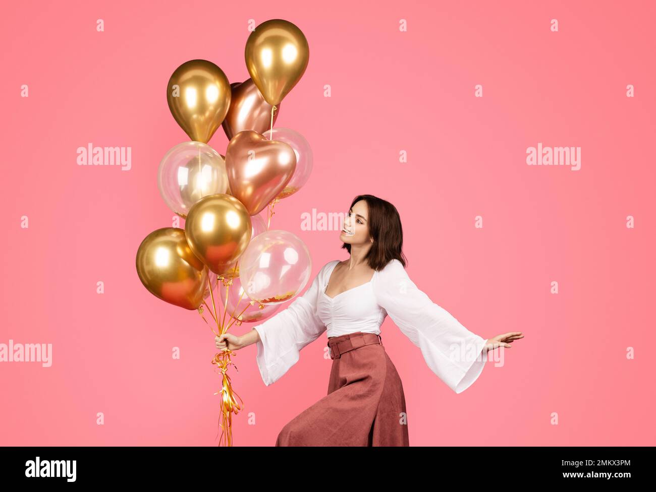 Smiling young caucasian female hold lot of inflatable balloons, dancing, enjoy party Stock Photo