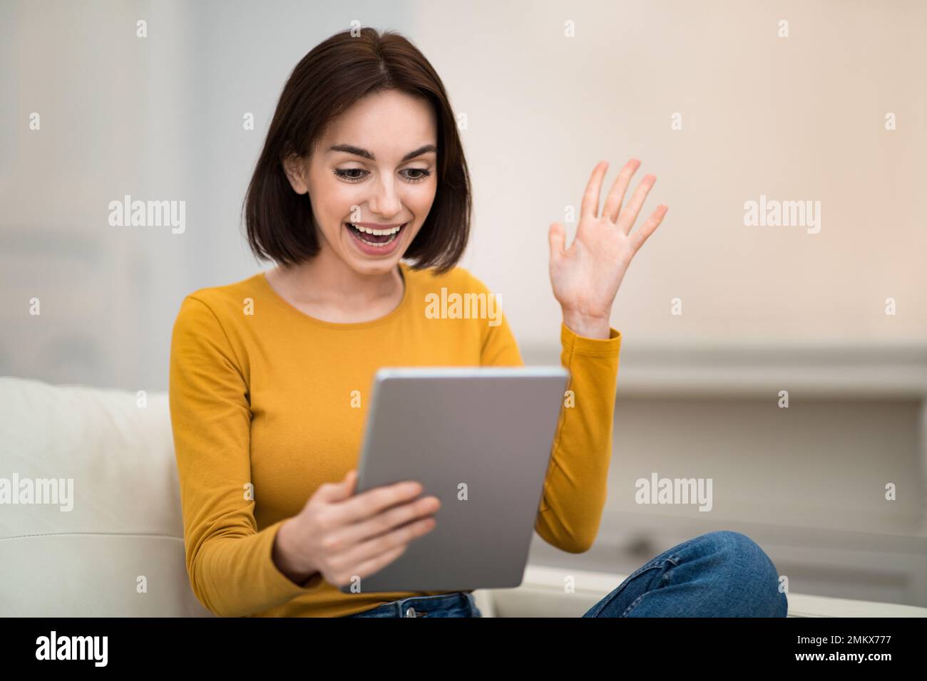 Excited young woman using digital tablet at home Stock Photo