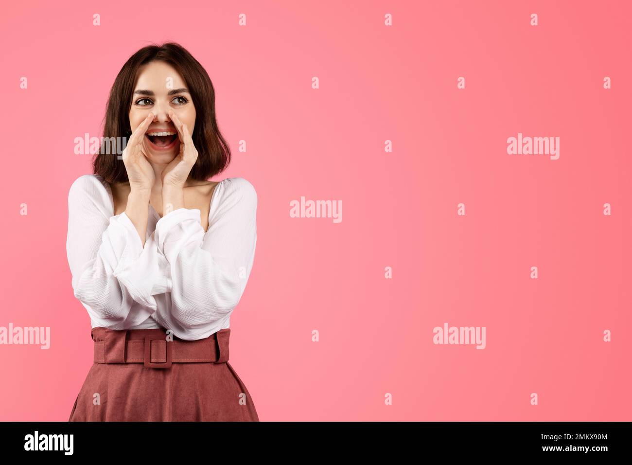 Happy young caucasian woman in casual puts her hands at open mouth, screaming near free space Stock Photo