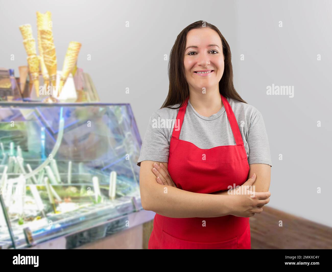 Smiling ice cream store employee standing behind the counter in the store with crossed arms Stock Photo