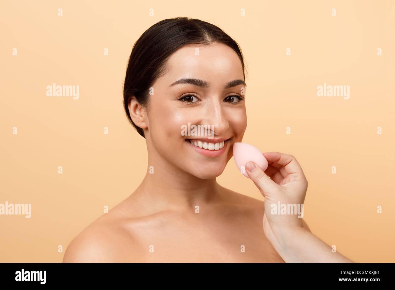 Hand With Beauty Blender Doing Makeup To Beautiful Young Indian Woman Stock Photo