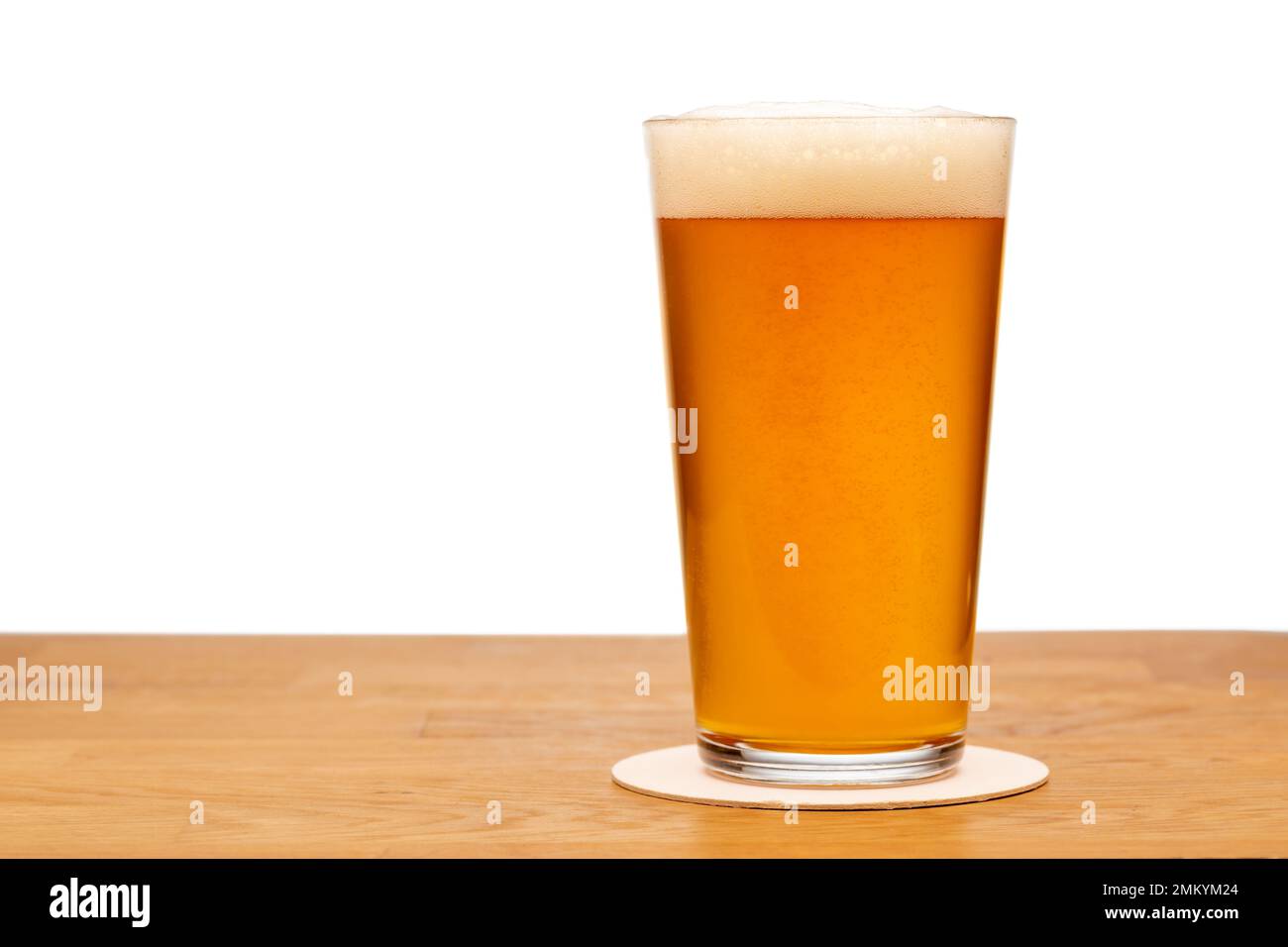 Full shaker pint glass of craft ale or beer on wooden table with white background Stock Photo