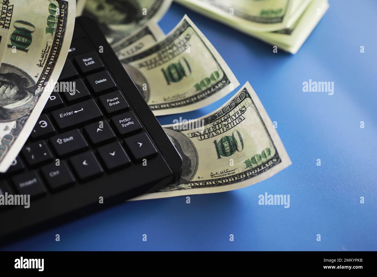 Computer keyboard and a scattering of 100 dollar bills on the table ...