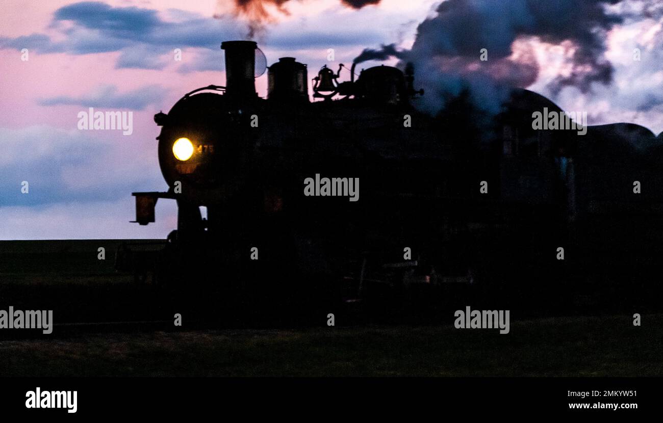 A Silhouette of a Classic Steam Engine Blowing Smoke and Steam Stock Photo