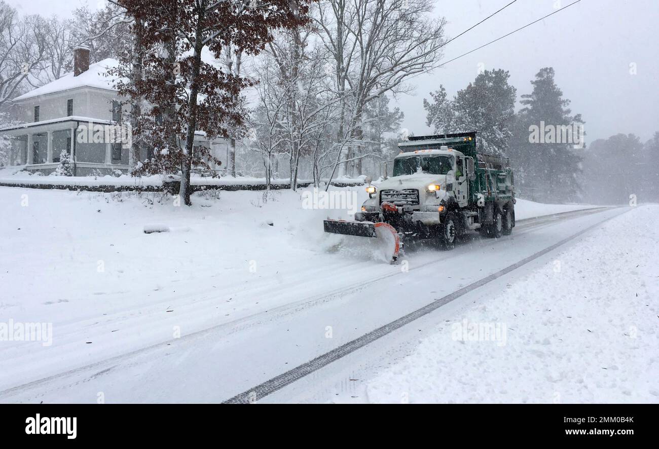 A snow plow moves on a snowy Durham, N.C., street after several inches fell on Sunday Dec. 9
