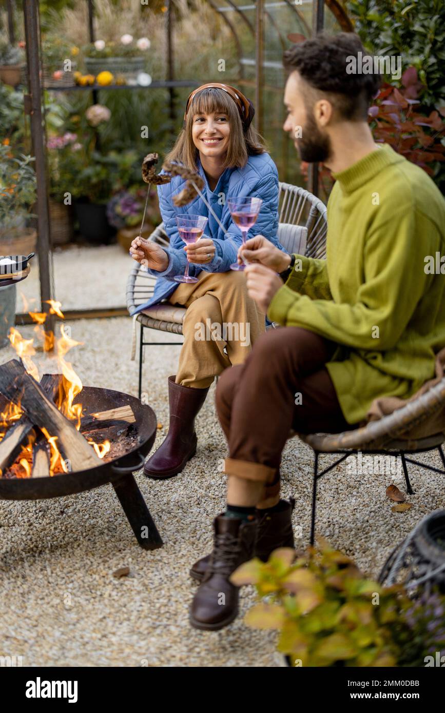Young couple spending dinner time by the fire at backyard Stock Photo