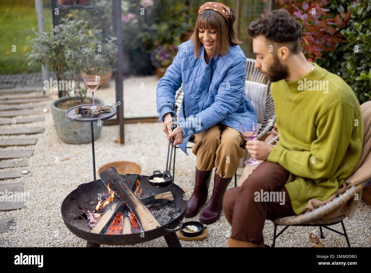 Young couple spending dinner time by the fire at backyard Stock Photo