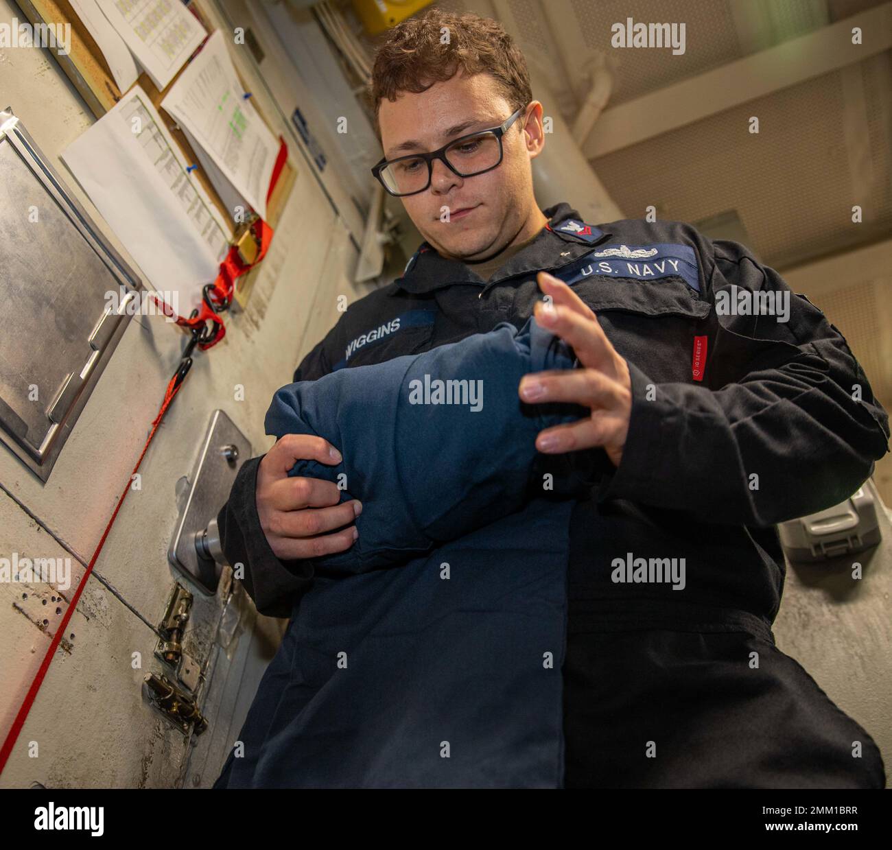 PHILIPPINE SEA (Sept. 13, 2022) Logistics Specialist 2nd Class Stephen Wiggins, from Atlanta, rolls coveralls for stowage in the storage room aboard Ticonderoga-class guided-missile cruiser USS Chancellorsville (CG 62) in the Philippine Sea on Sept. 13, 2022. Chancellorsville is forward-deployed to the U.S. 7th Fleet in support of security and stability in the Indo-Pacific and is assigned to Commander, Task Force 70, a combat-ready force that protects and defends the collective maritime interest of its allies and partners in the region. Stock Photo