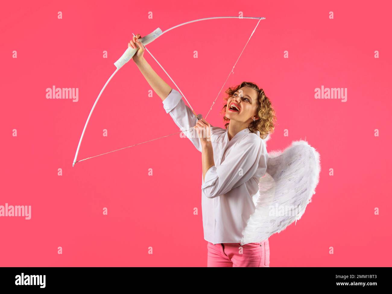 Angel girl aiming up with bow and arrow. February 14. Saint Valentines Day. Arrows of love. Cupid. Stock Photo
