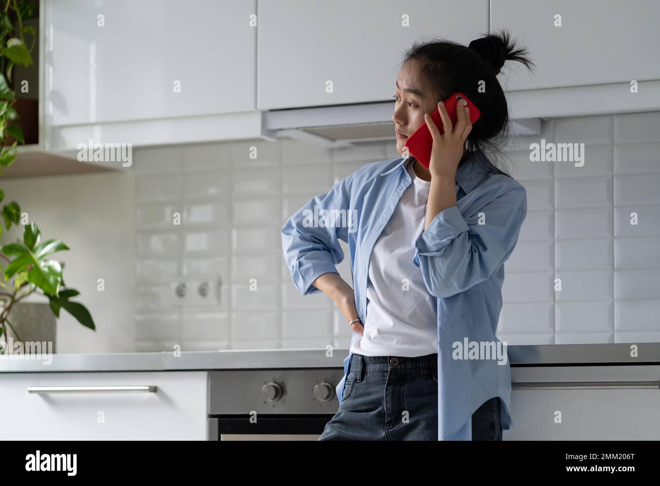 Worried upset Asian woman standing alone in kitchen making unpleasant ...