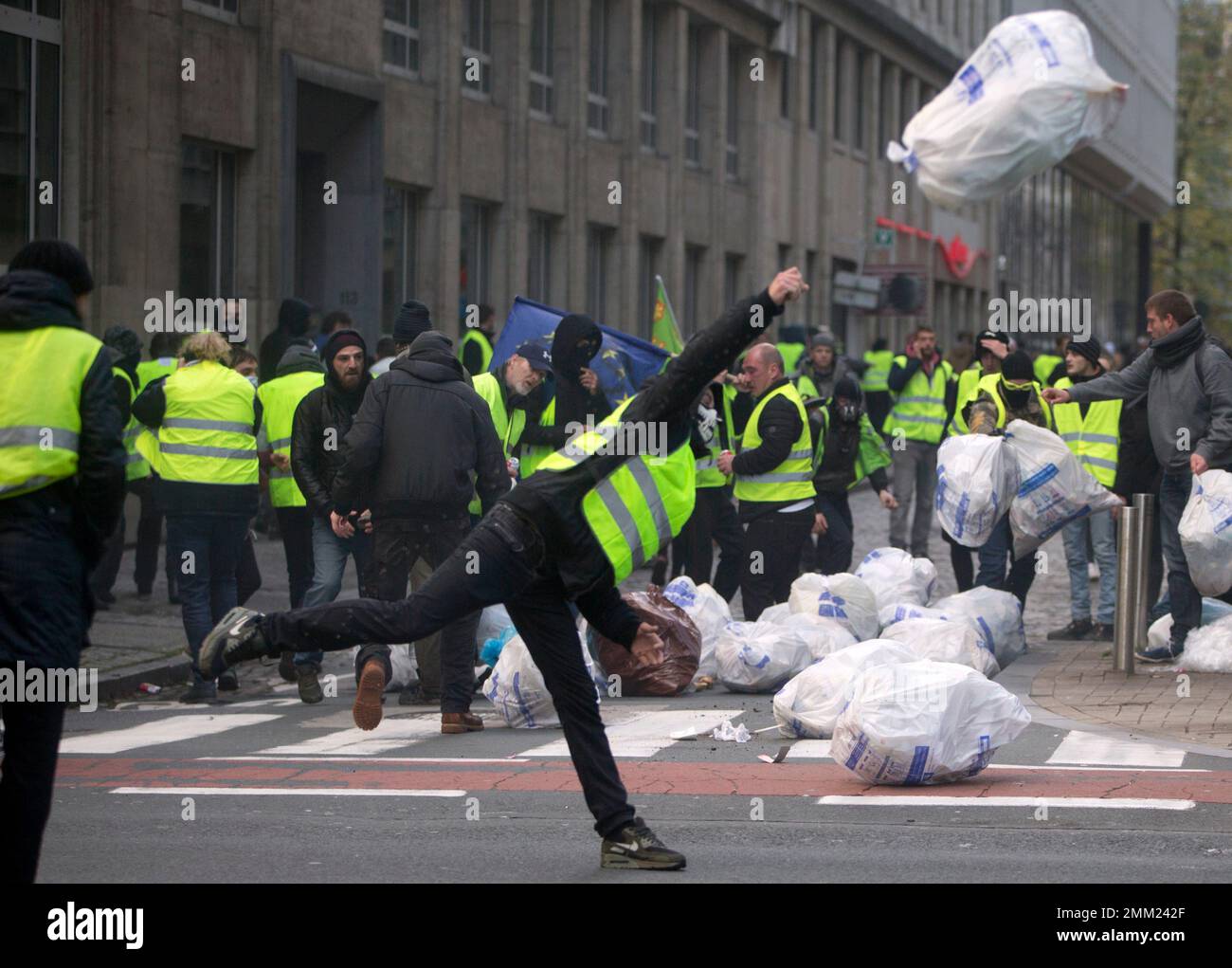 A demonstrator throws a garbage bag during a protest of the yellow jackets  in Brussels, Friday, Nov. 30, 2018. The demonstrators are protesting  against rising fuel prices. (AP Photo/Virginia Mayo Stock Photo -