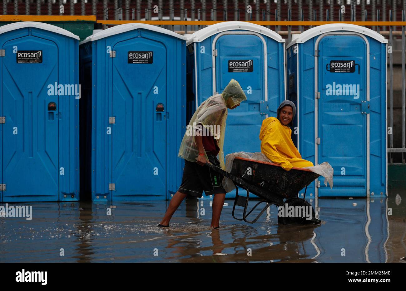A man pushes a friend in a wheelbarrow through flood waters, after ...