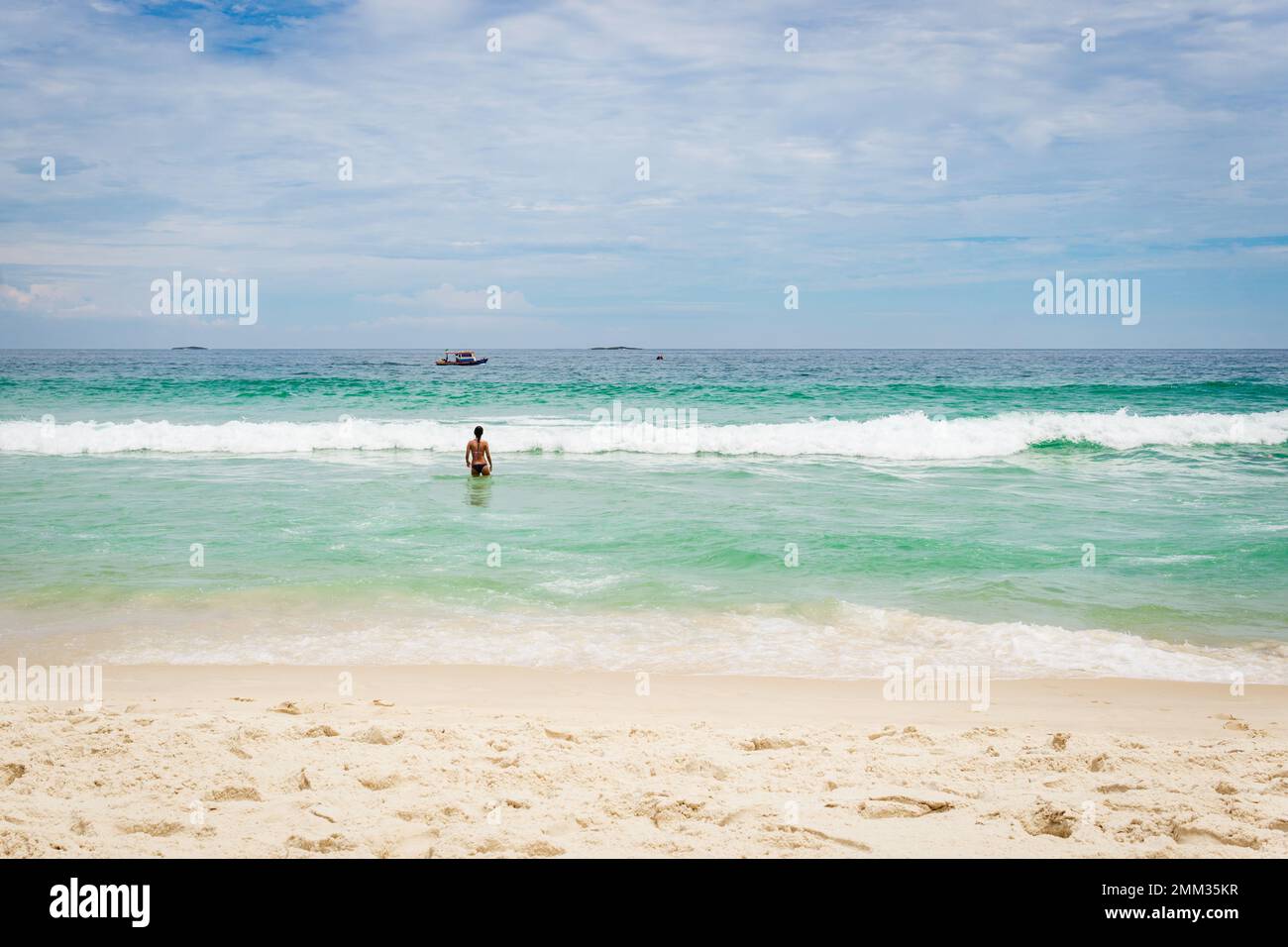 Back view of Brazilian woman entering the ocean at Barra da Tijuca beach in Rio de Janeiro, Brazil. Stock Photo