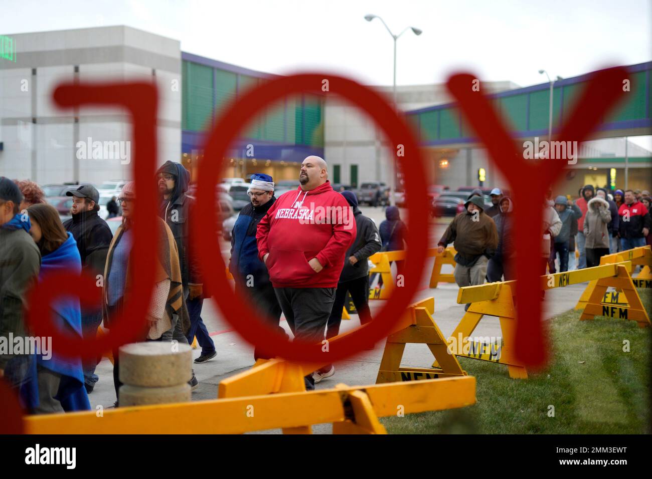 Black Friday shoppers walk between barriers to enter the Nebraska