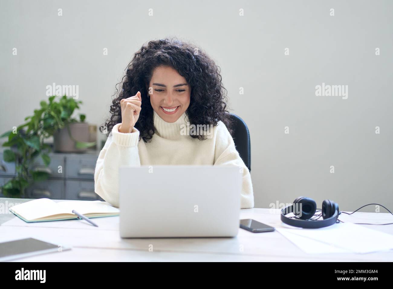 Happy young woman student or employee using laptop feeling excited. Stock Photo