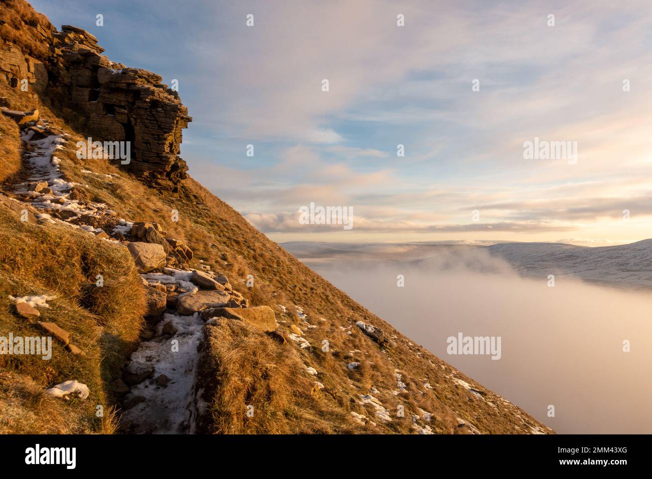 Looking up the final exposed snowy path towards the summit of Pen-y-ghent mountain at sunrise with mist and snow in the Yorkshire Dales National Park, Stock Photo