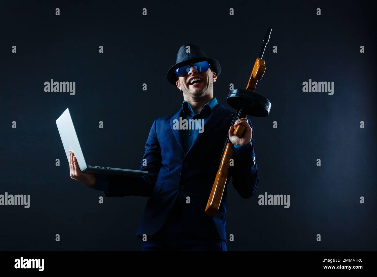 businessman in sunglasses with machine gun and laptop Stock Photo Alamy