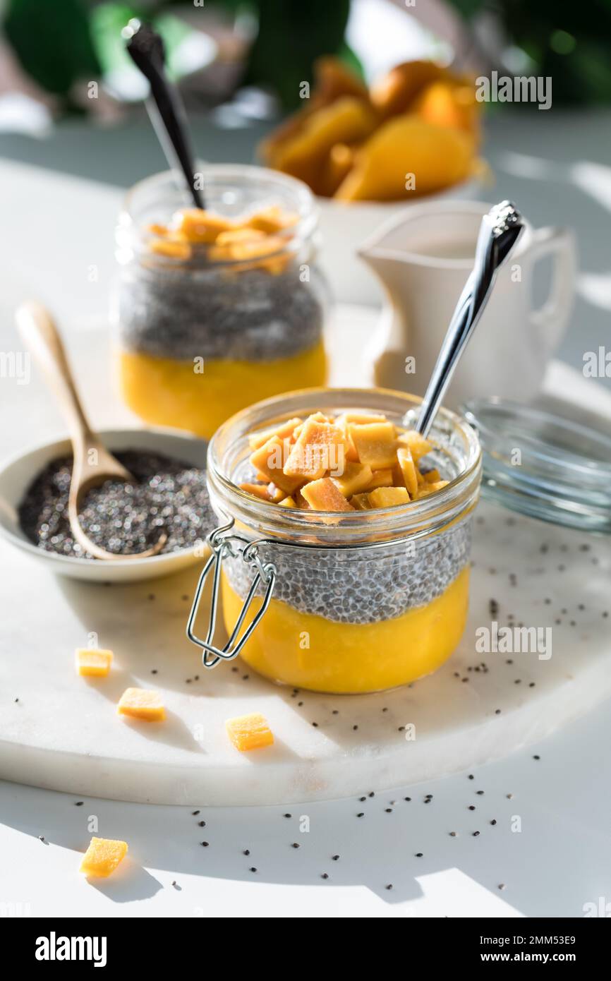 Pureed mango chia pudding snacks on a marble slab on a table in bright sunlight. Stock Photo