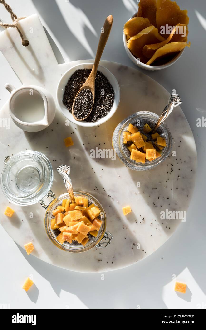 Above view of a marble board topped with mango chia puddings and all the fixings Stock Photo