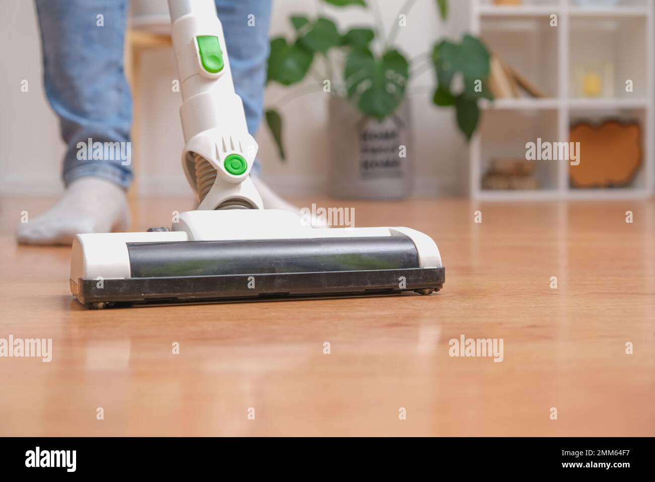 Cleaning room with modern wireless vacuum cleaner without cord. A man