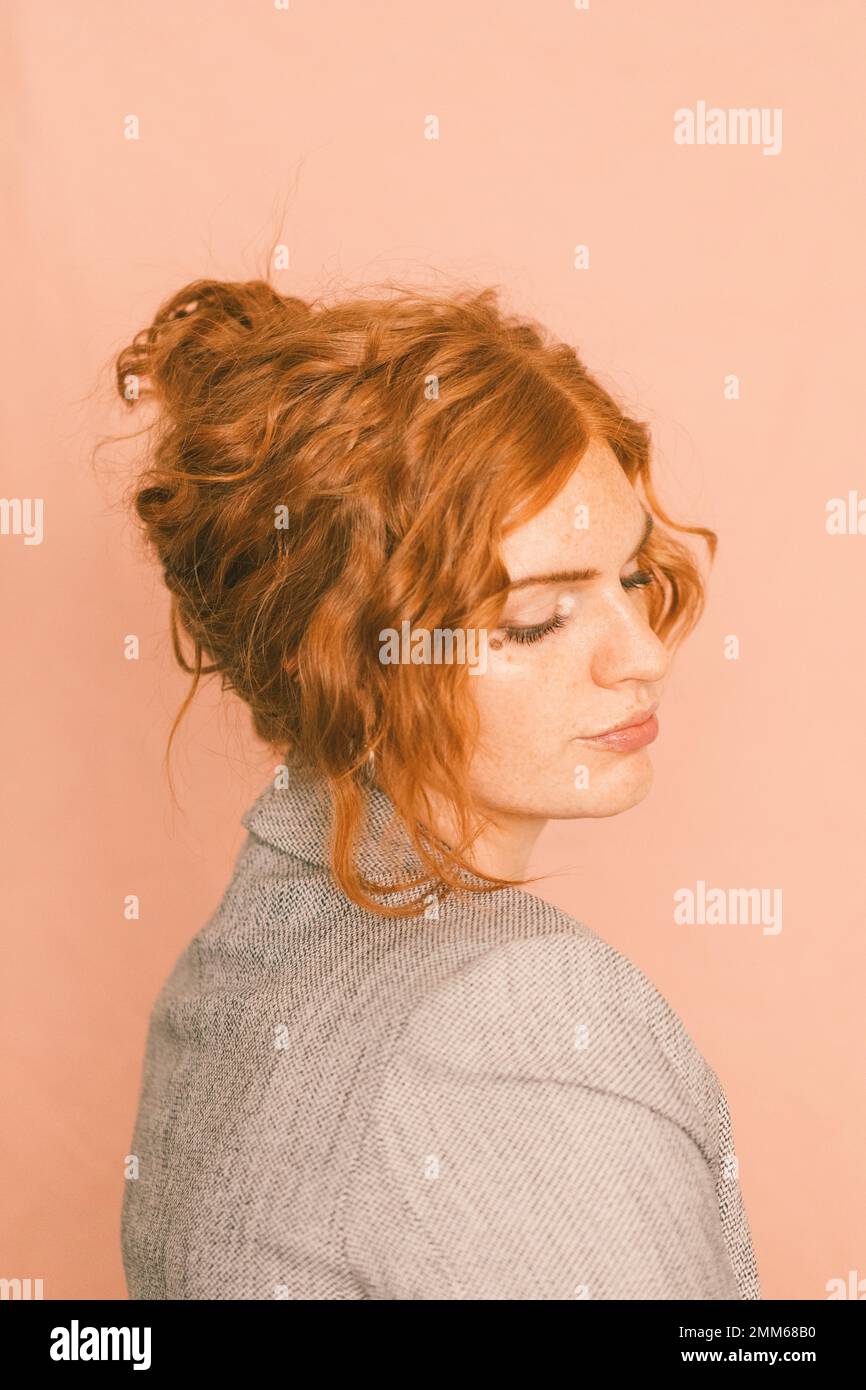 A feminine business woman in suitcoat against pink background Stock Photo